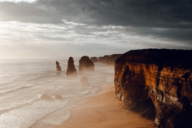 Partly cloudy sky over a beach leading up to a clifface